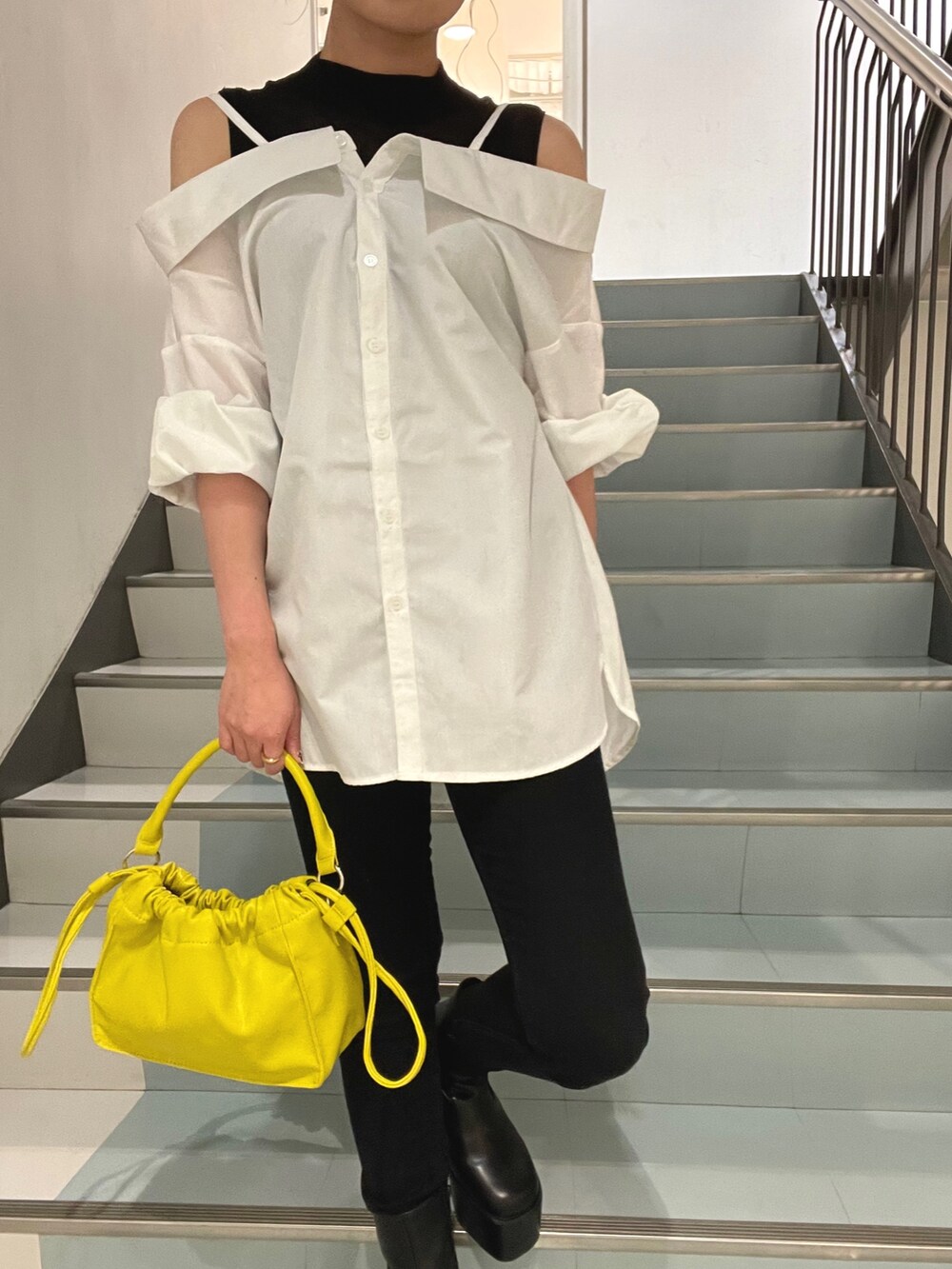 イエロー系のハンドバッグ、ホワイト系のシャツ/ブラウス、ブラック系のブーツを着用したレディースの夏コーディネートの7枚目の写真