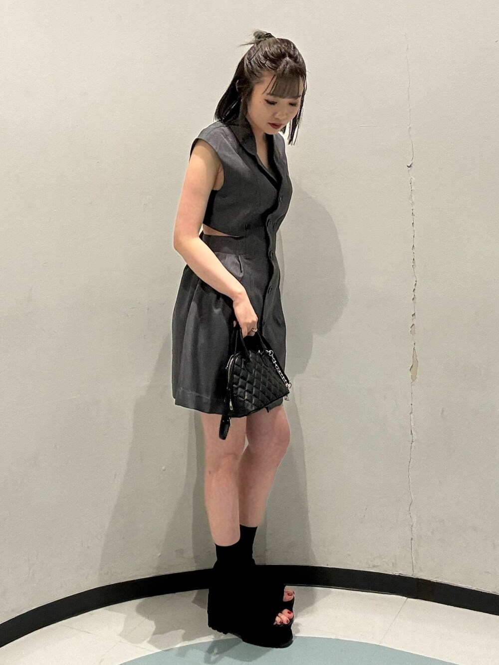 ブラック系のハンドバッグ、グレー系のワンピースを着用したレディースの春コーディネートの2枚目の写真