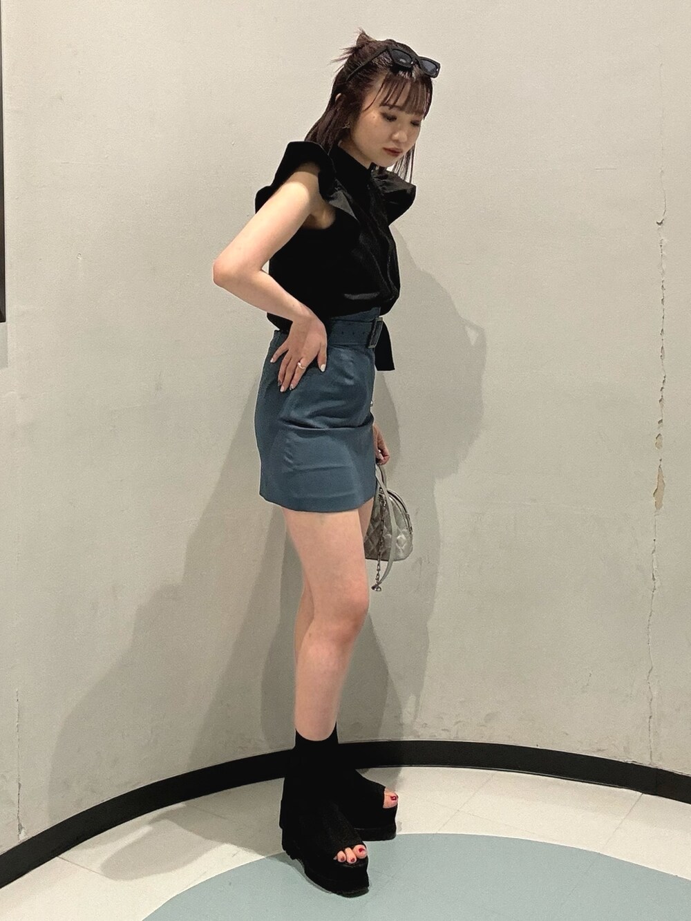 ブラック系のシャツ/ブラウス、ブルー系のスカート、ブラック系のブーツを着用したレディースの春コーディネートの2枚目の写真