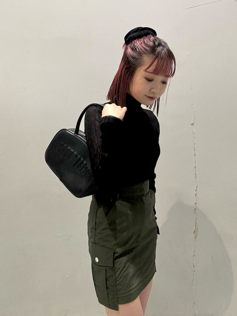 ブラック系のニット/セーター、ホワイト系のベスト、グリーン系のスカートを着用したレディースの秋コーディネートの5枚目の写真