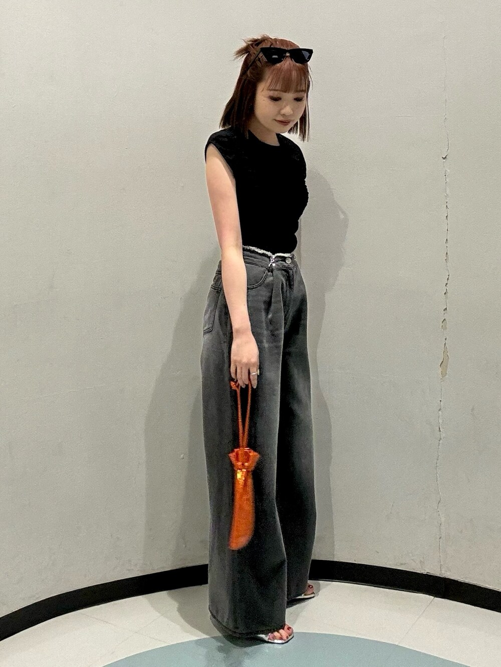 オレンジ系のショルダーバッグ、ブラック系のTシャツ/カットソー、ブラック系のデニムパンツを着用したレディースの夏コーディネートの2枚目の写真