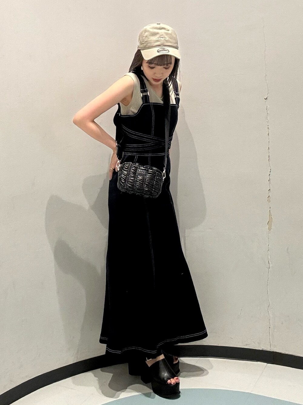 ベージュ系のニット/セーター、ブルー系のジャンパースカート、ブラック系のショルダーバッグを着用したレディースの春コーディネートの2枚目の写真