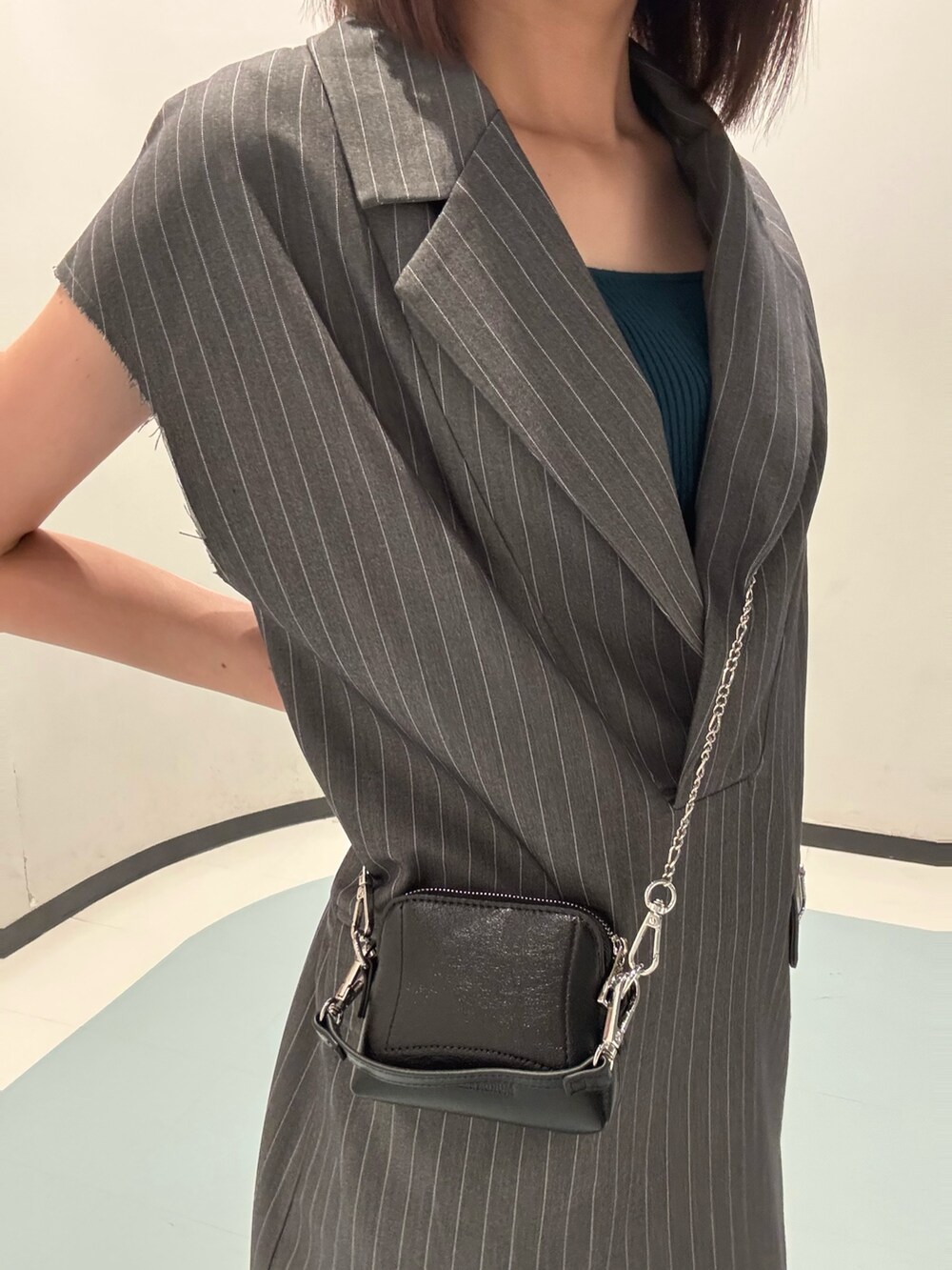 ブラック系のショルダーバッグ、ブラック系のサンダル、グレー系のワンピースを着用したレディースの夏コーディネートの4枚目の写真