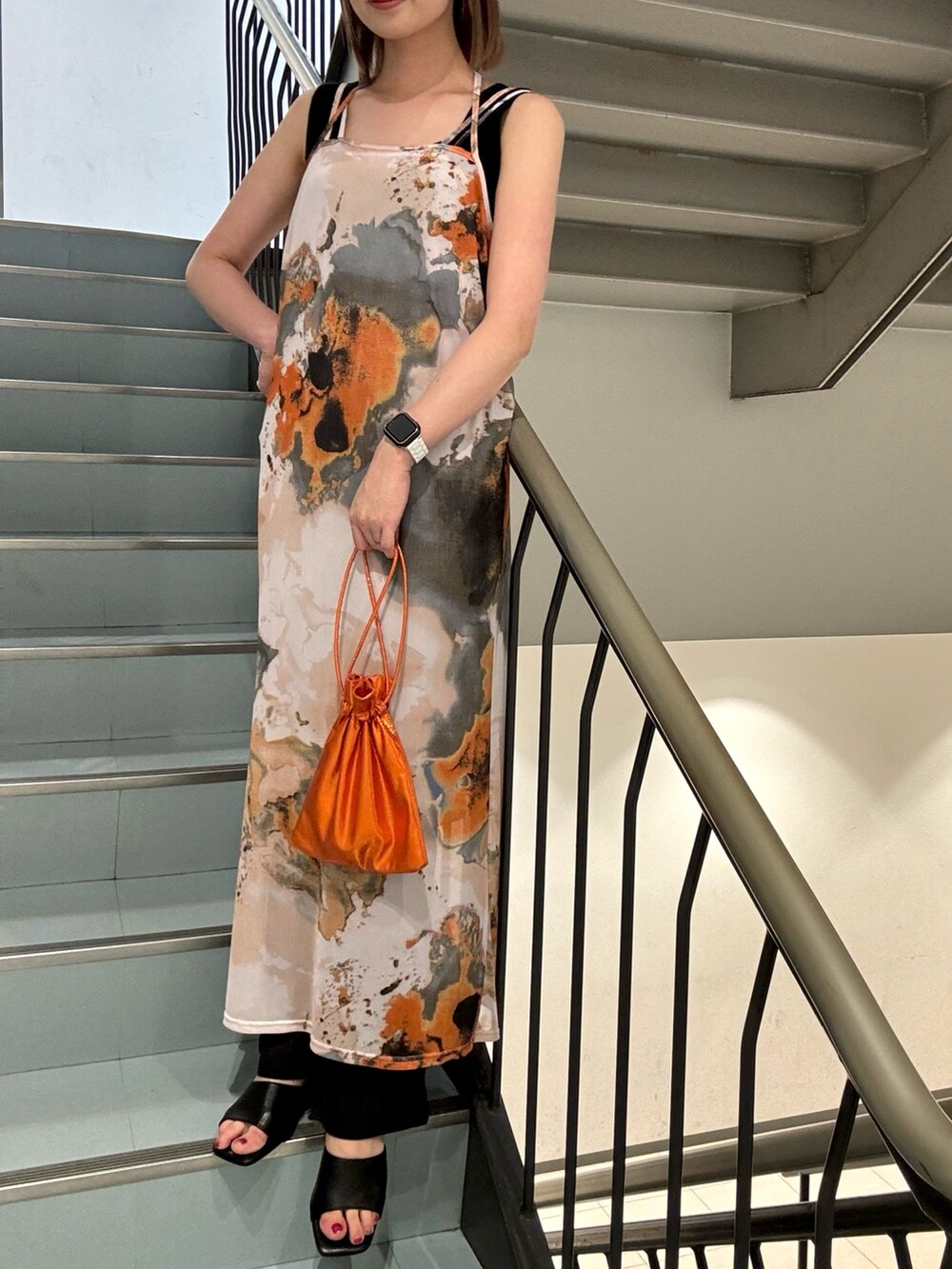 オレンジ系のショルダーバッグ、ブラック系のニット/セーター、オレンジ系のワンピースを着用したレディースの夏コーディネートの5枚目の写真