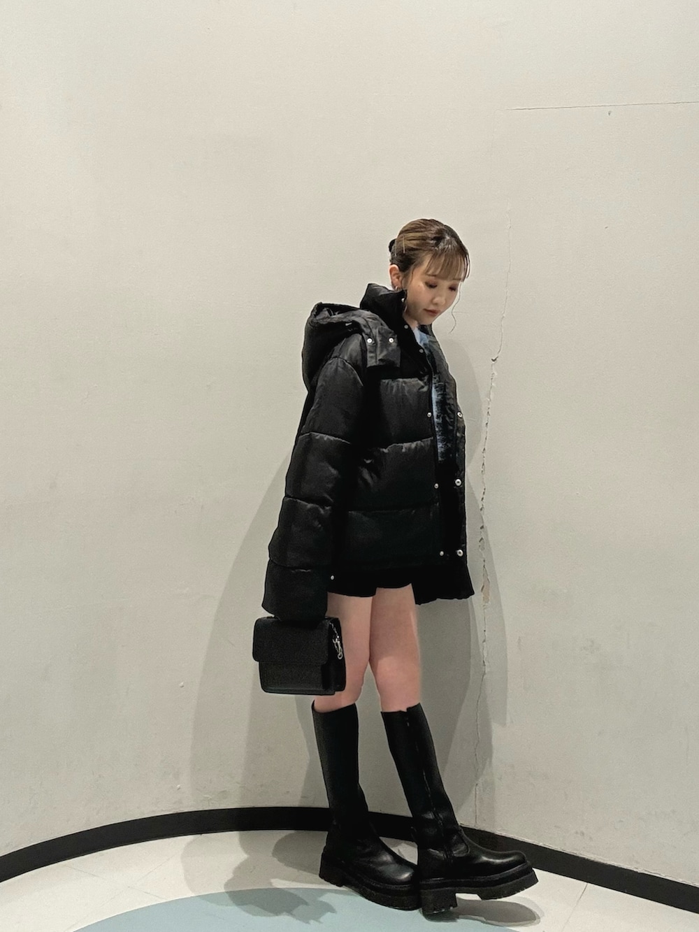 ブラック系のハンドバッグ、ブラック系のブルゾン、ブルー系のニット/セーターを着用したレディースの冬コーディネートの3枚目の写真