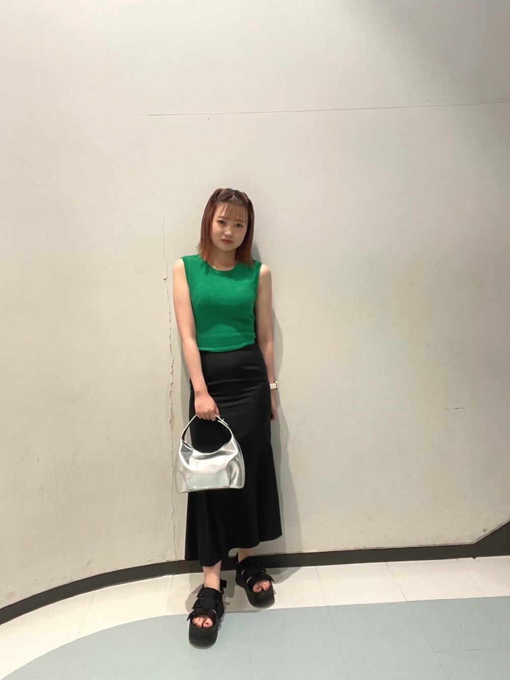 ブラック系のスカート、グリーン系のタンクトップ、ブラック系のサンダルを着用したレディースの春コーディネートの2枚目の写真