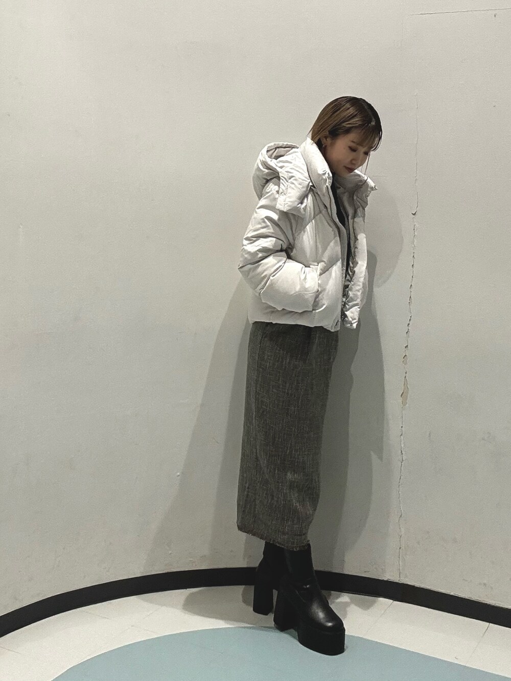 グレー系のダウンジャケット/コート、ブラック系のニット/セーター、グレー系のワンピースを着用したレディースの冬コーディネートの2枚目の写真