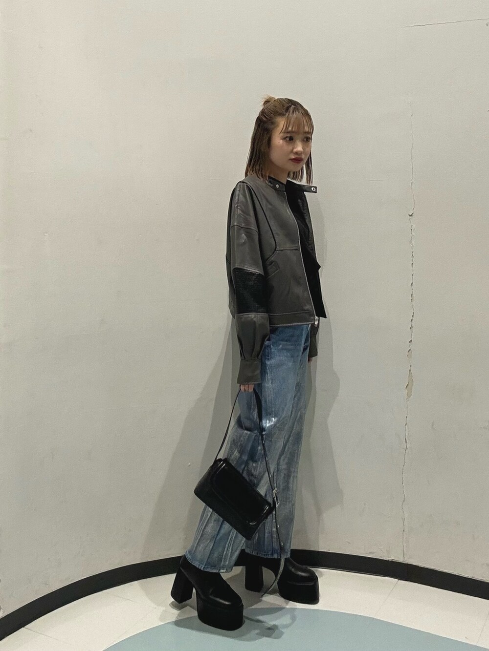 ブルー系のデニムパンツ、ブラック系のショルダーバッグ、グレー系のブルゾンを着用したレディースの冬コーディネートの2枚目の写真