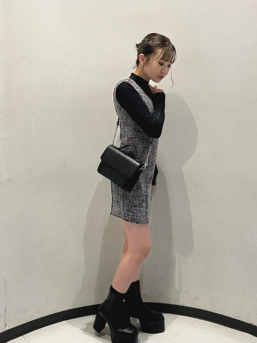 ブラック系のハンドバッグ、ブラック系のニット/セーター、ブラック系のワンピースを着用したレディースの冬コーディネートの2枚目の写真