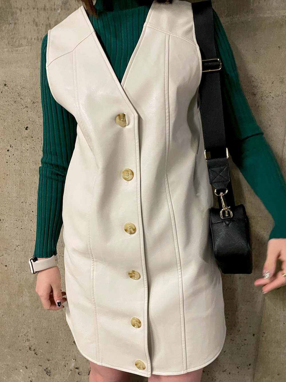 ブラック系のショルダーバッグ、グリーン系のニット/セーター、ホワイト系のワンピースを着用したレディースの冬コーディネートの4枚目の写真