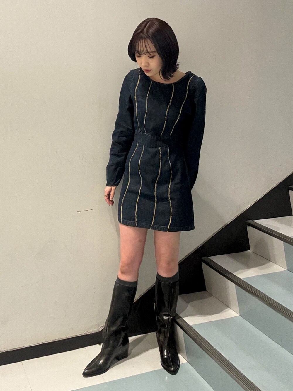 ブラック系のショルダーバッグ、ブラック系のブーツ、ブルー系のワンピースを着用したレディースの冬コーディネートの5枚目の写真