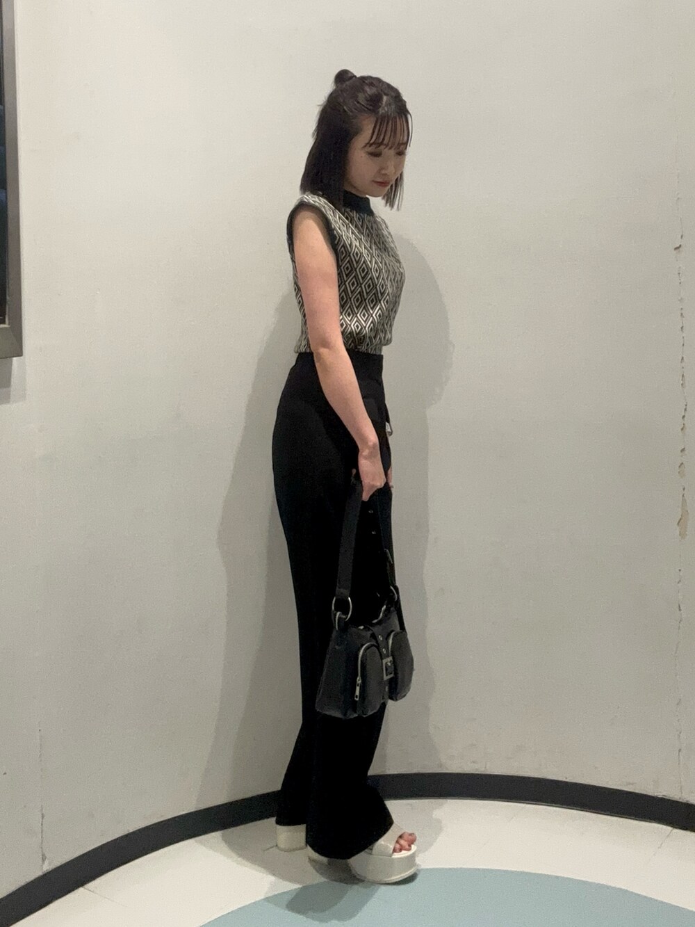 ホワイト系のサンダル、ブラック系のハンドバッグ、グリーン系のタンクトップを着用したレディースの夏コーディネートの2枚目の写真