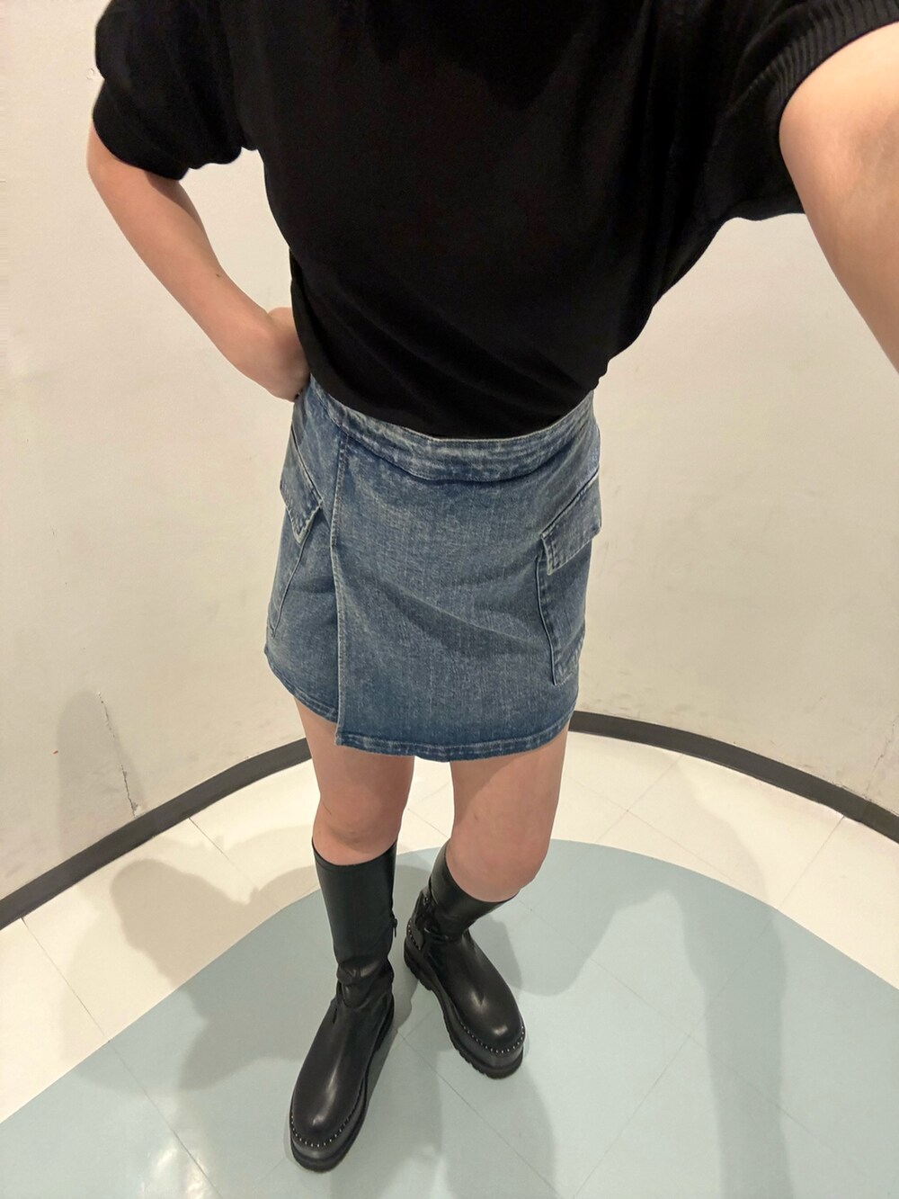 ブラック系のニット/セーター、ブルー系のスカート、ブラック系のブーツを着用したレディースの夏コーディネートの4枚目の写真