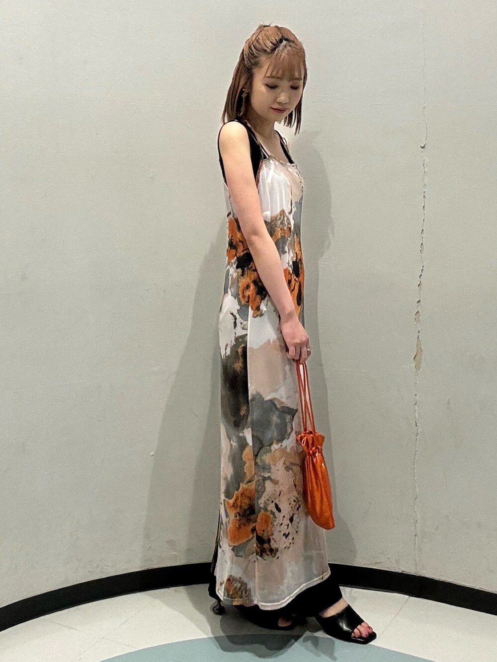 オレンジ系のショルダーバッグ、ブラック系のニット/セーター、オレンジ系のワンピースを着用したレディースの夏コーディネートの2枚目の写真