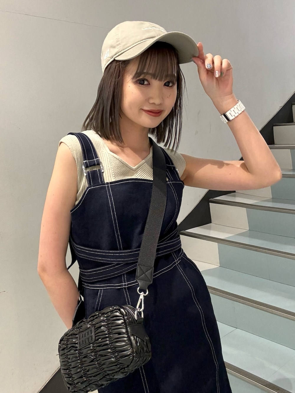 ベージュ系のニット/セーター、ブルー系のジャンパースカート、ブラック系のショルダーバッグを着用したレディースの春コーディネートの7枚目の写真