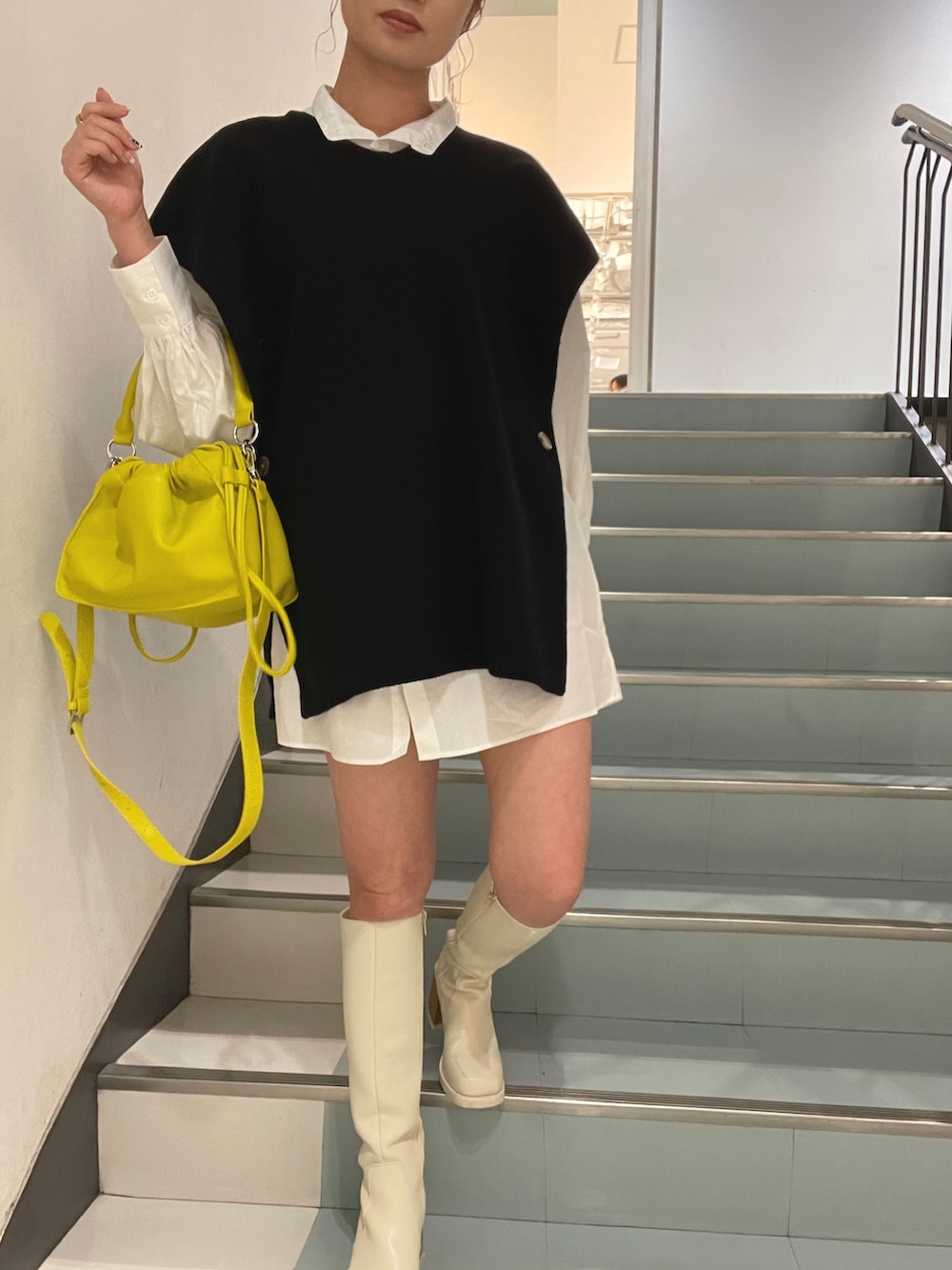 イエロー系のハンドバッグ、ブラック系のワンピースを着用したレディースの夏コーディネートの4枚目の写真