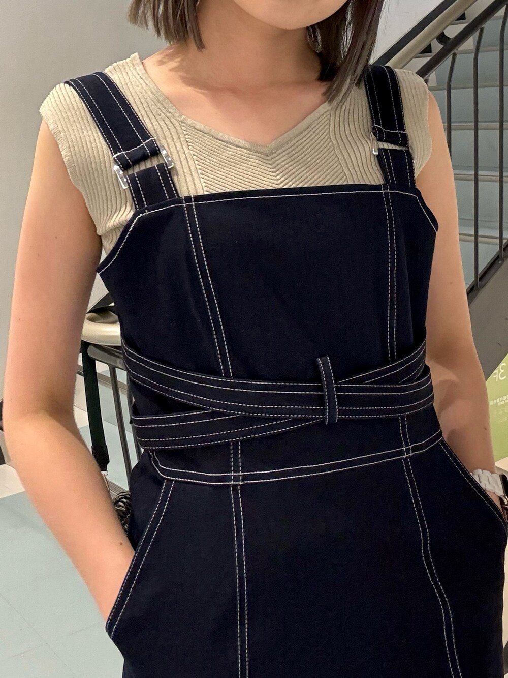 ベージュ系のニット/セーター、ブルー系のジャンパースカート、ブラック系のショルダーバッグを着用したレディースの春コーディネートの4枚目の写真