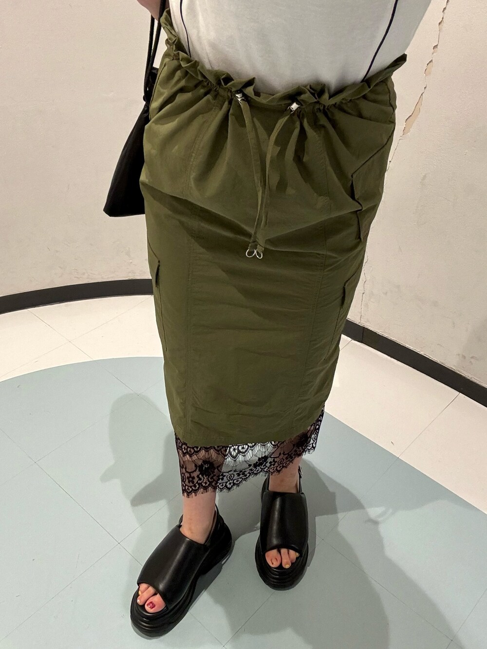 ホワイト系のTシャツ/カットソー、グリーン系のスカート、ブラック系のサンダルを着用したレディースの夏コーディネートの5枚目の写真