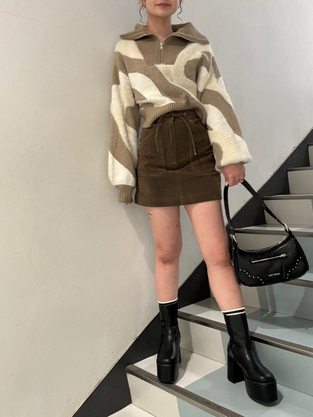 ホワイト系のニット/セーター、ブラウン系のスカート、ブラック系のブーツを着用したレディースの秋コーディネートの6枚目の写真
