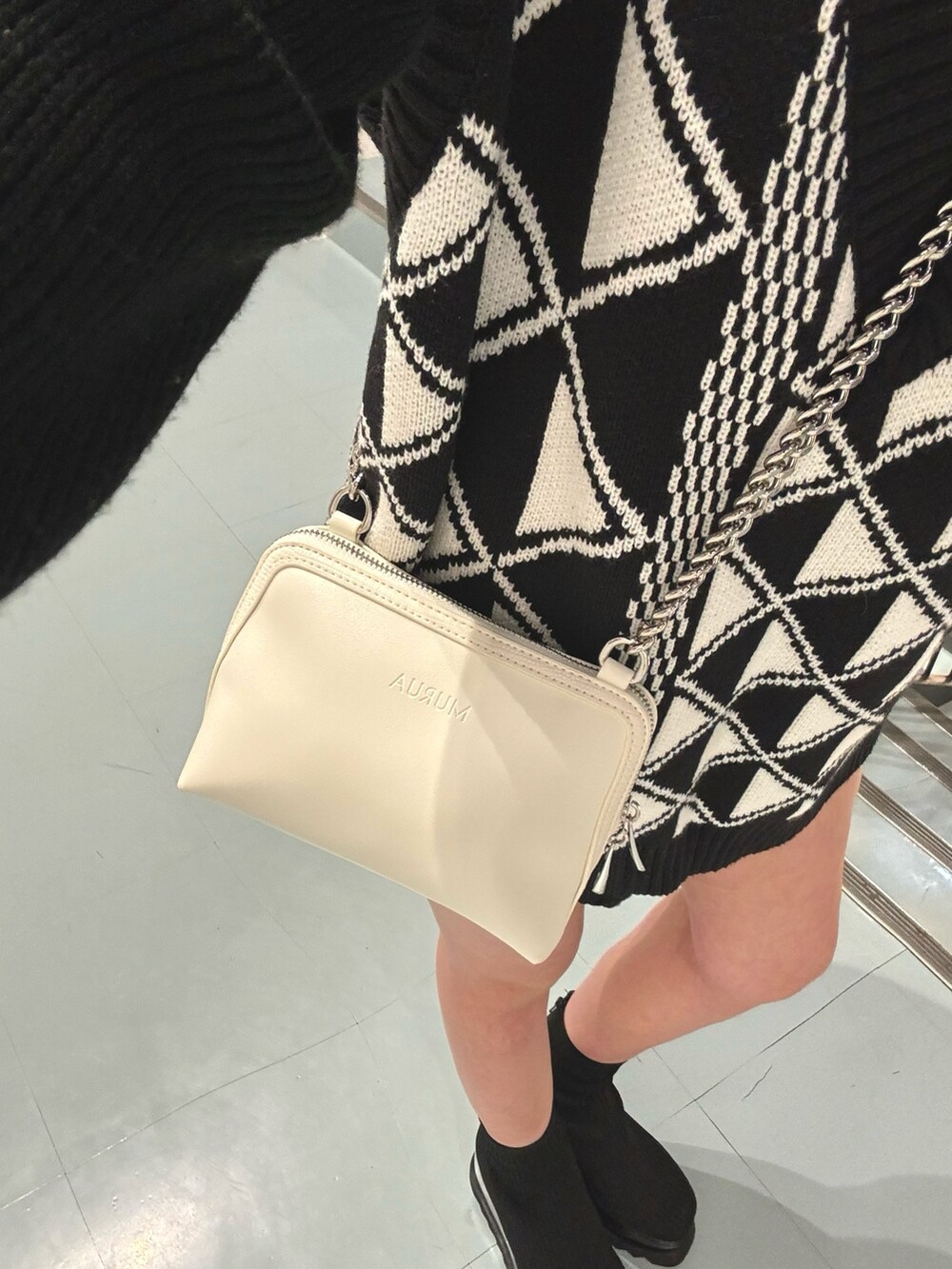 ブラック系のブーツ、ホワイト系のハンドバッグ、その他のベストを着用したレディースの冬コーディネートの6枚目の写真