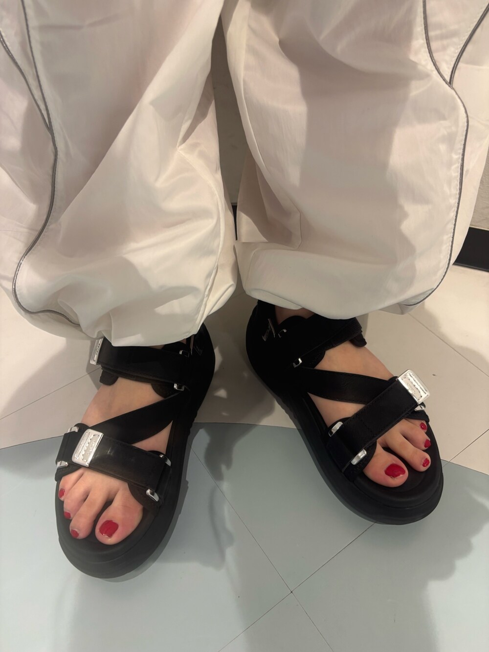 ブラック系のニット/セーター、ホワイト系のカーゴパンツ、ブラック系のサンダルを着用したレディースの春コーディネートの7枚目の写真