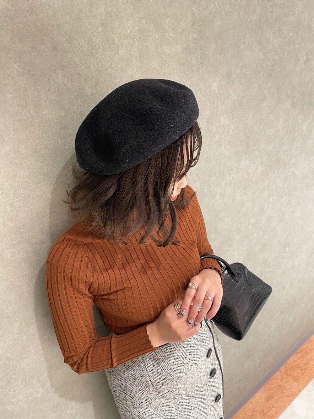 ホワイト系のブーツ、ブラック系のハンドバッグ、ホワイト系のスカートを着用したレディースの秋コーディネートの3枚目の写真