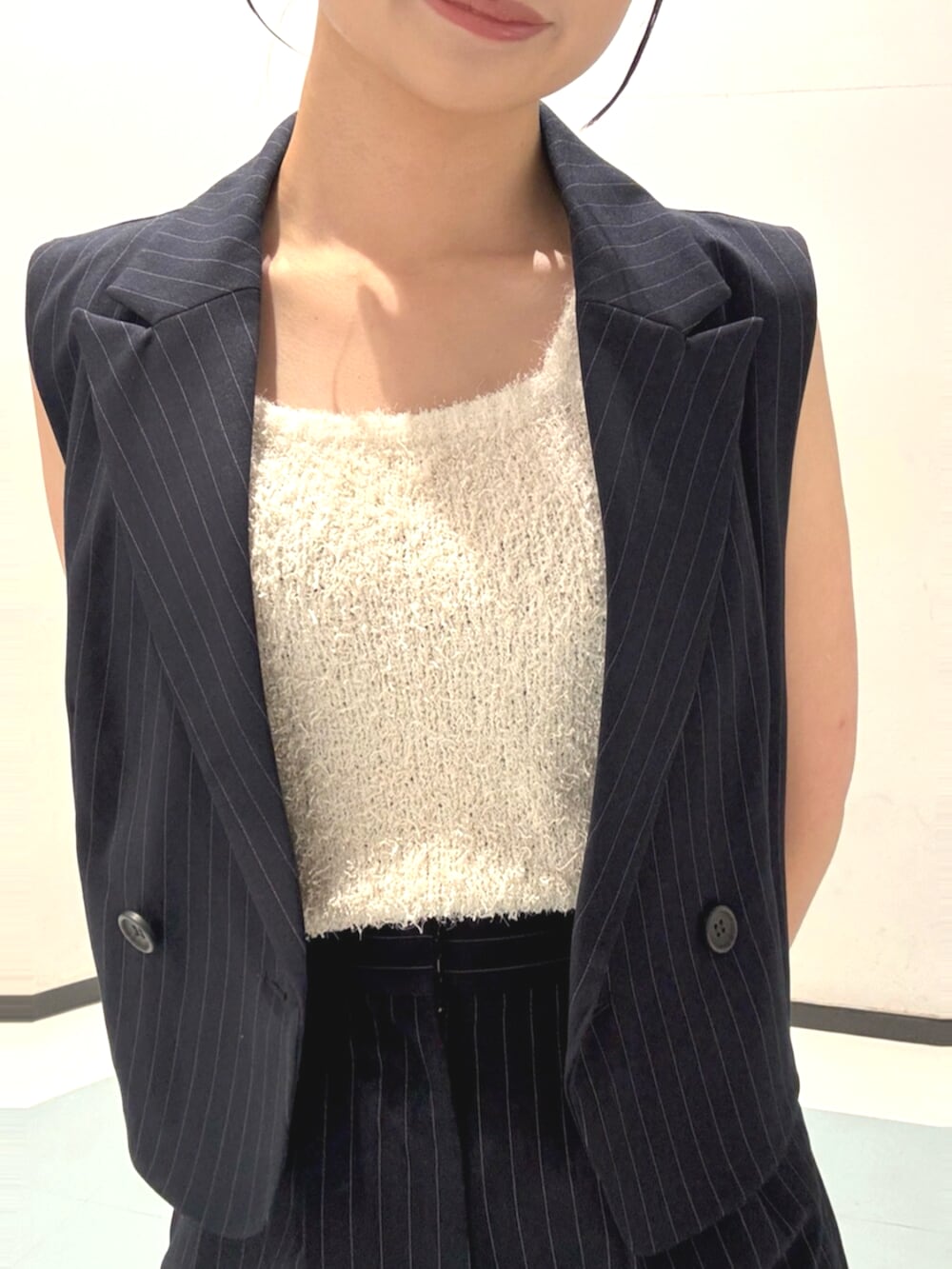 ブラック系のサンダル、ホワイト系のニット/セーター、ブルー系のベストを着用したレディースの夏コーディネートの5枚目の写真