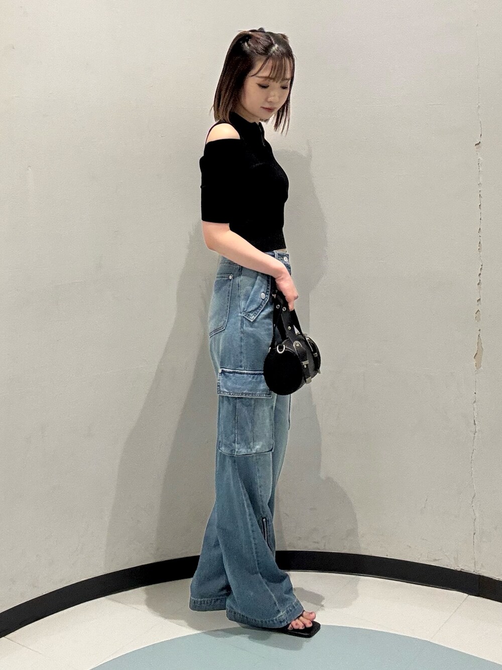 ブラック系のニット/セーター、ブラック系のハンドバッグ、ブラック系のサンダルを着用したレディースの夏コーディネートの2枚目の写真