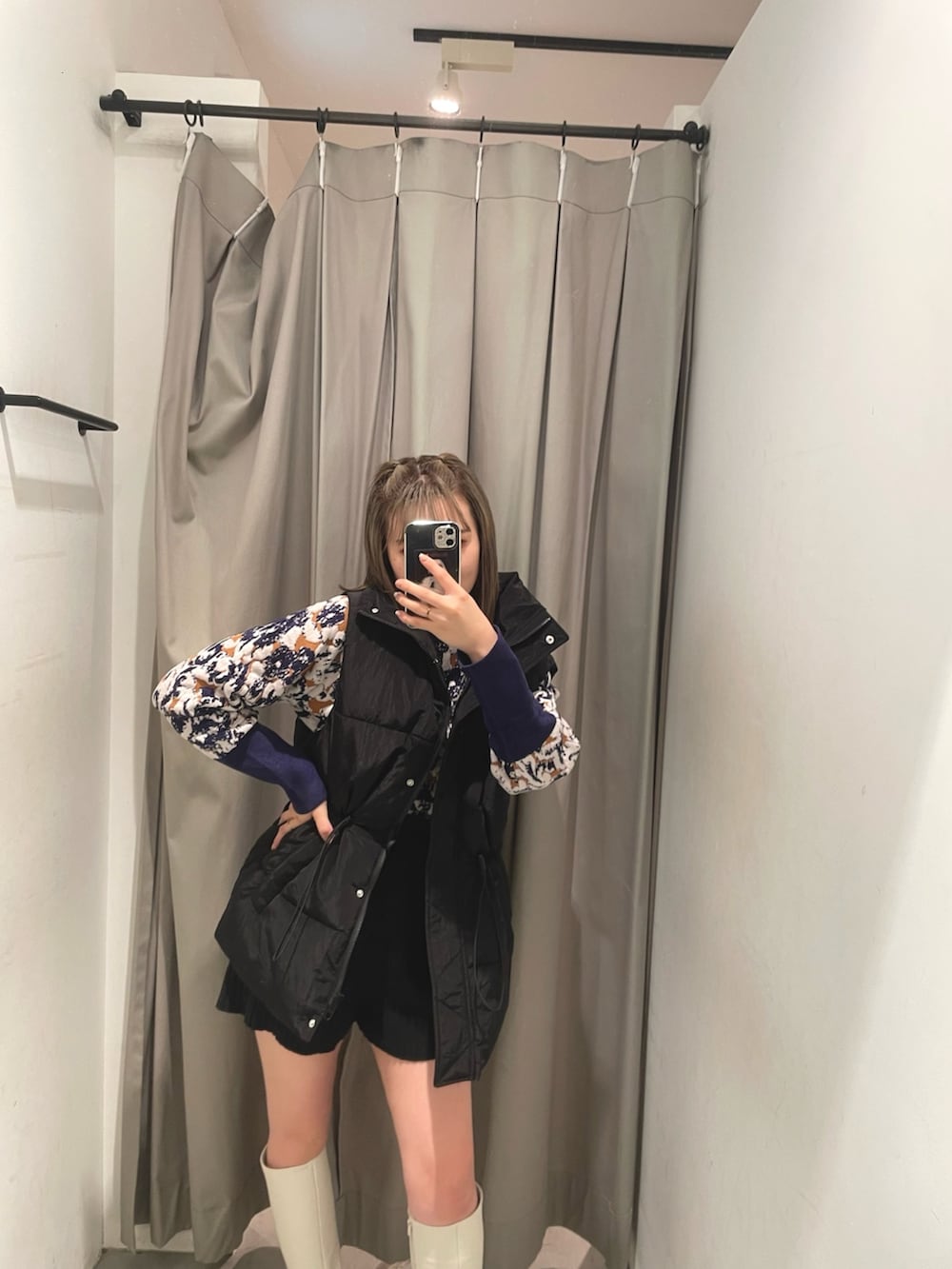 グリーン系のハンドバッグ、ブラック系のダウンベスト、ホワイト系のブーツを着用したレディースの秋コーディネートの4枚目の写真