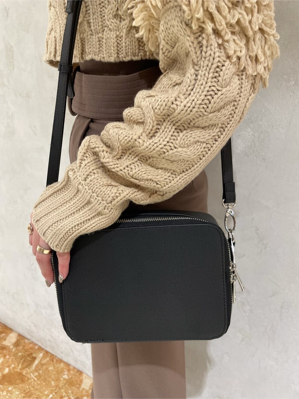 ベージュ系のスカート、ブラック系のショルダーバッグ、ブラック系のブーツを着用したレディースの秋コーディネートの2枚目の写真