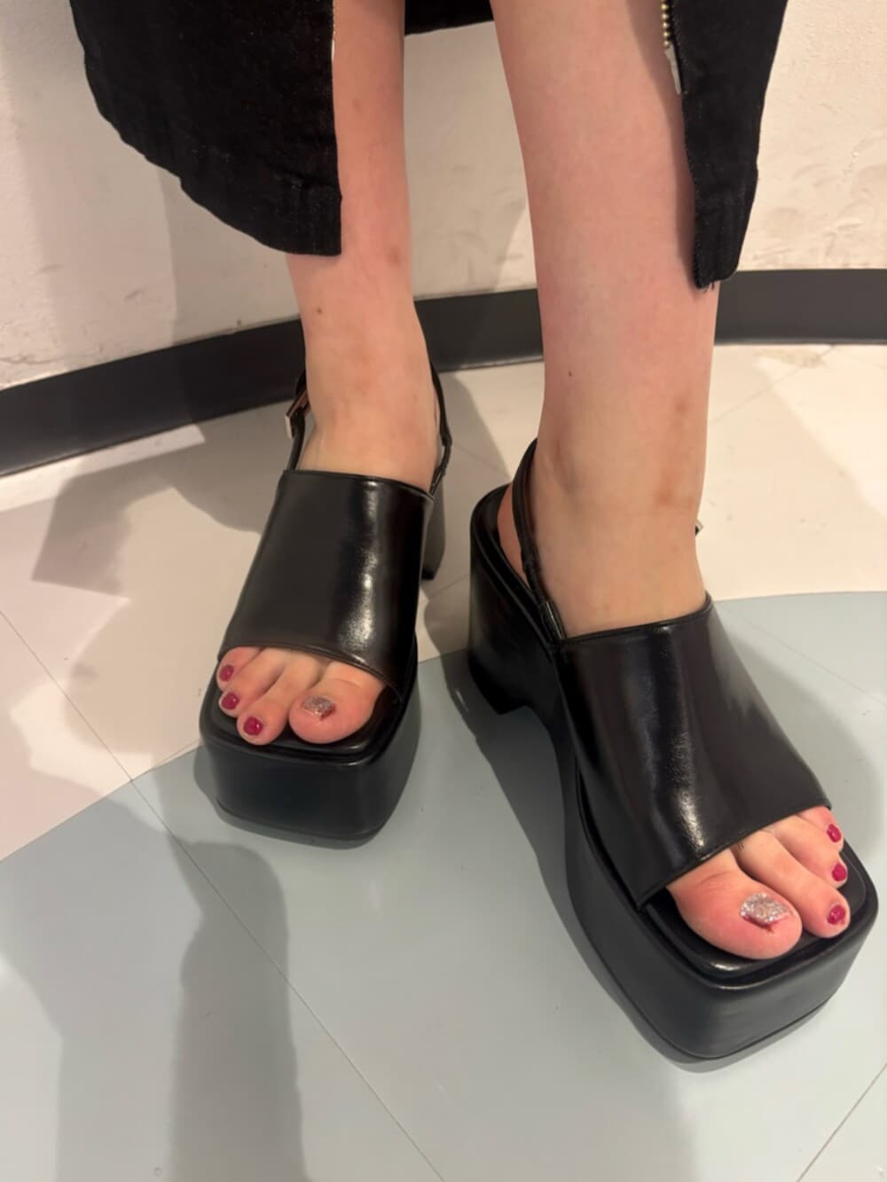 ブラック系のサンダル、グリーン系のタンクトップ、ブラック系のハンドバッグを着用したレディースの夏コーディネートの7枚目の写真