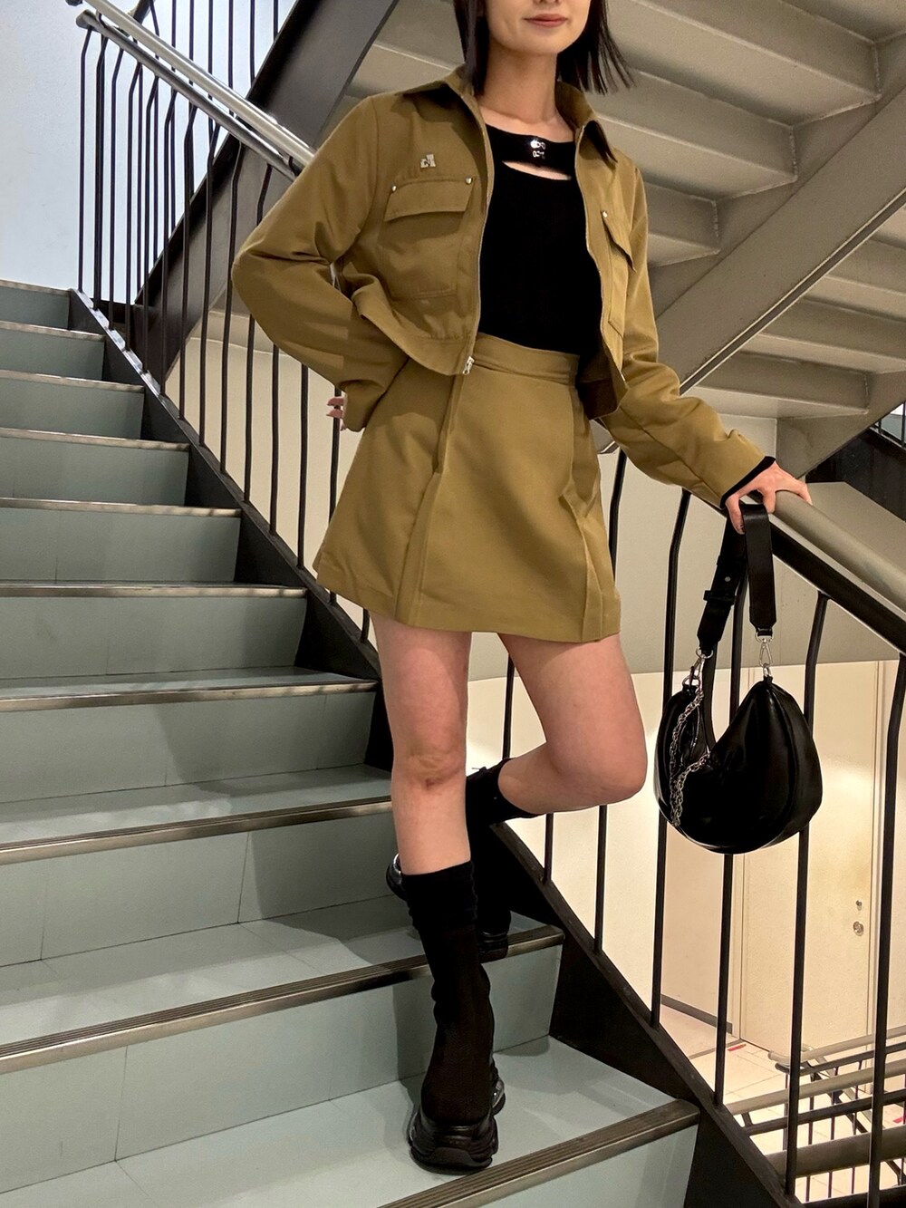 ブラック系のショルダーバッグ、ベージュ系のスカート、ベージュ系のブルゾンを着用したレディースの春コーディネートの6枚目の写真