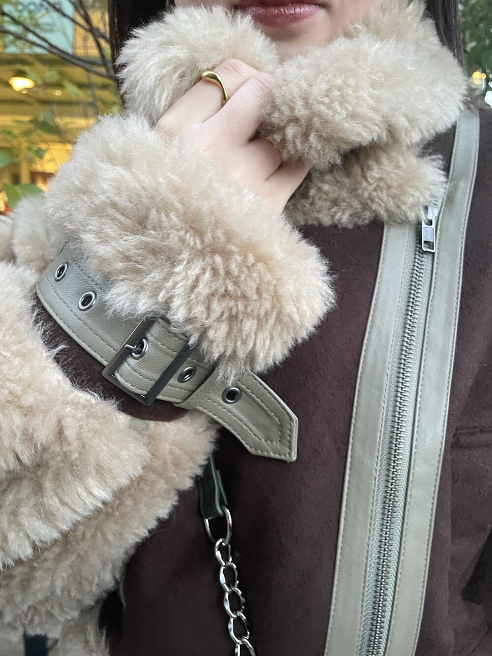 ブラウン系のムートンコート、グリーン系のショルダーバッグ、ブラック系のワンピースを着用したレディースの冬コーディネートの4枚目の写真