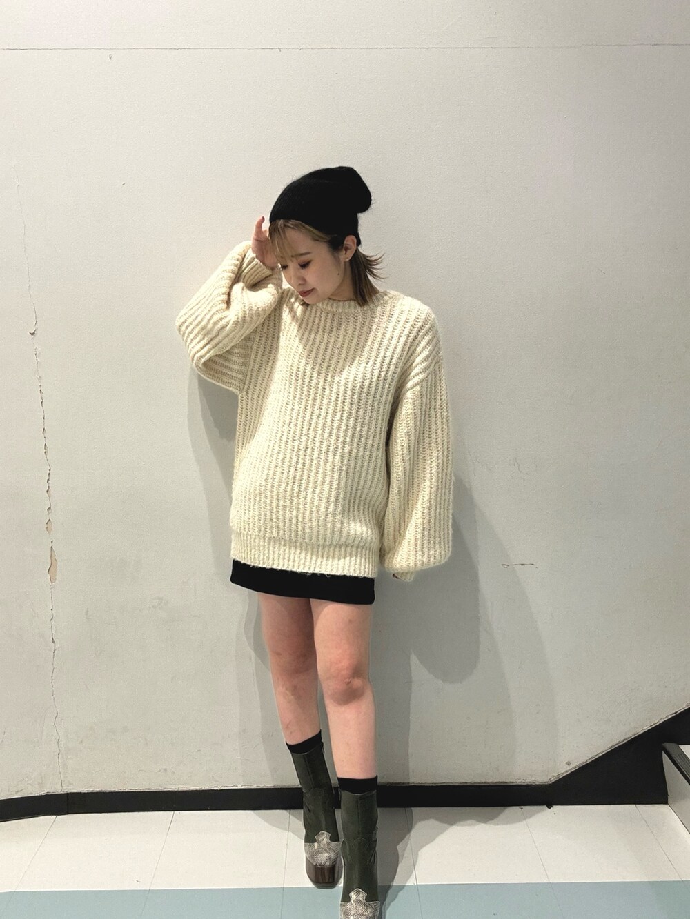 ブラック系のスカート、ホワイト系のニット/セーター、グリーン系のブーツを着用したレディースの秋コーディネートの4枚目の写真