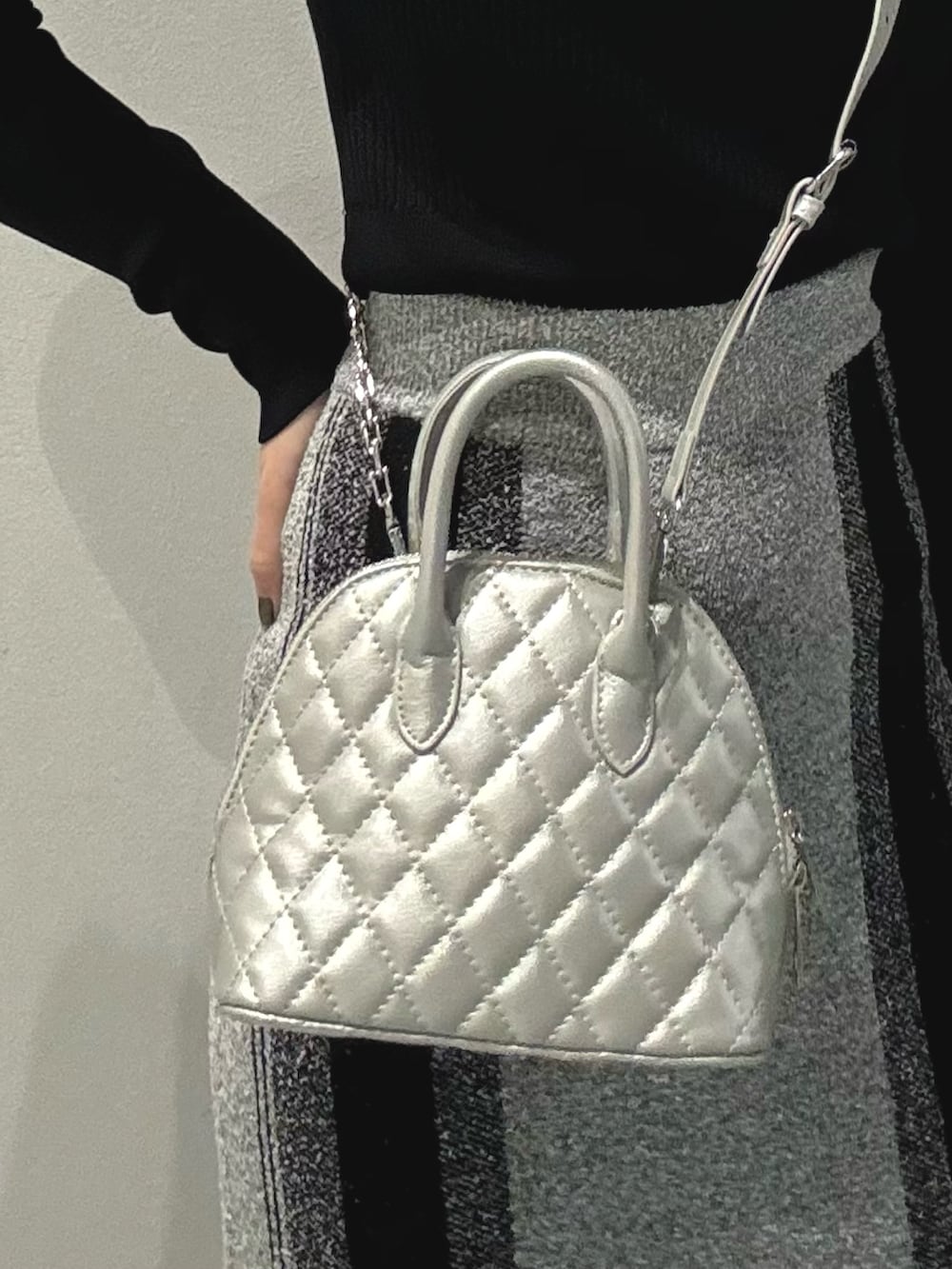 ブラック系のブーツ、シルバー系のハンドバッグ、グレー系のスカートを着用したレディースの冬コーディネートの6枚目の写真