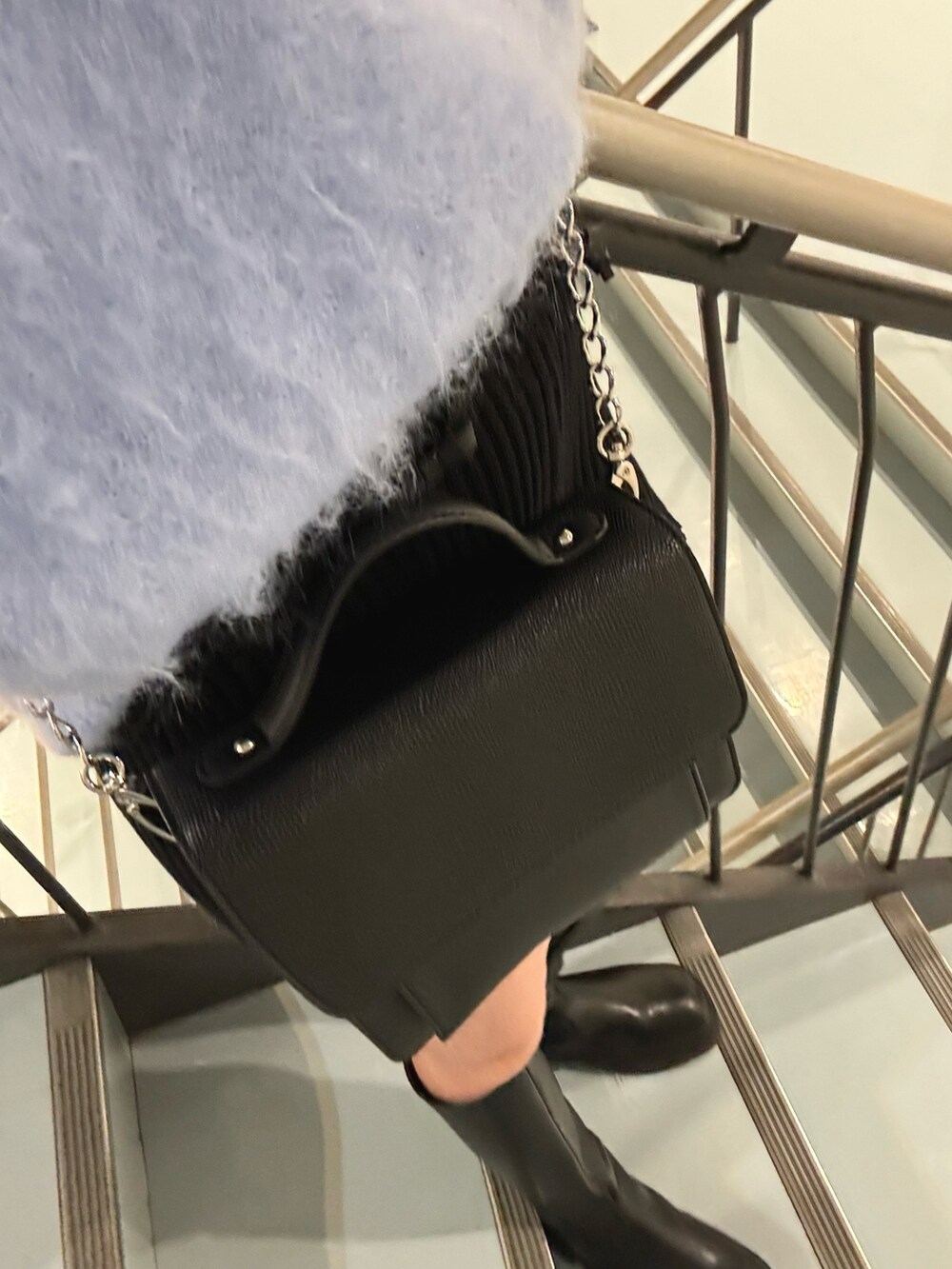 ブラック系のハンドバッグ、ブラック系のブルゾン、ブルー系のニット/セーターを着用したレディースの冬コーディネートの6枚目の写真