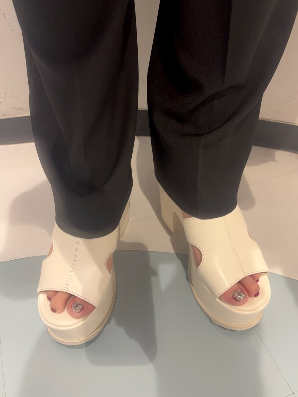 ホワイト系のサンダル、ブラック系のハンドバッグ、グリーン系のタンクトップを着用したレディースの夏コーディネートの7枚目の写真