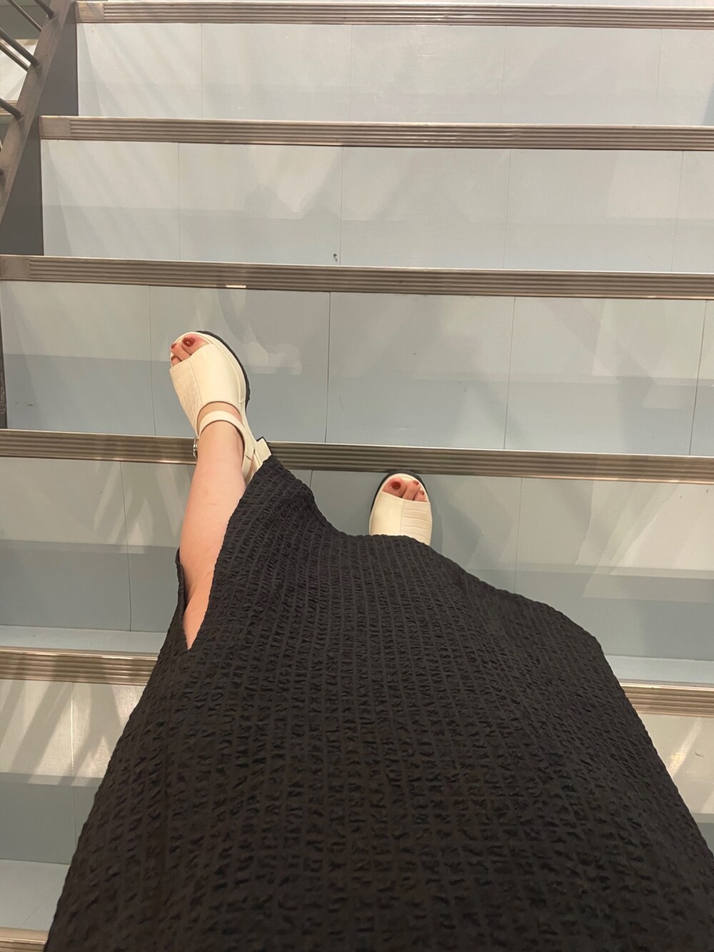 ブラック系のショルダーバッグ、ホワイト系のサンダル、ブルー系のタンクトップを着用したレディースの春コーディネートの6枚目の写真