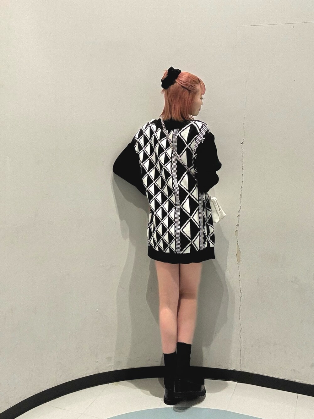 ブラック系のブーツ、ホワイト系のハンドバッグ、その他のベストを着用したレディースの冬コーディネートの3枚目の写真