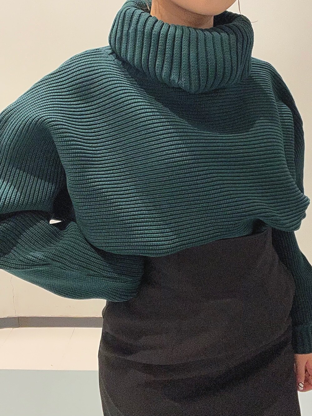 グリーン系のニット/セーター、ブラック系のブーツ、ブラック系のスカートを着用したレディースの秋コーディネートの7枚目の写真