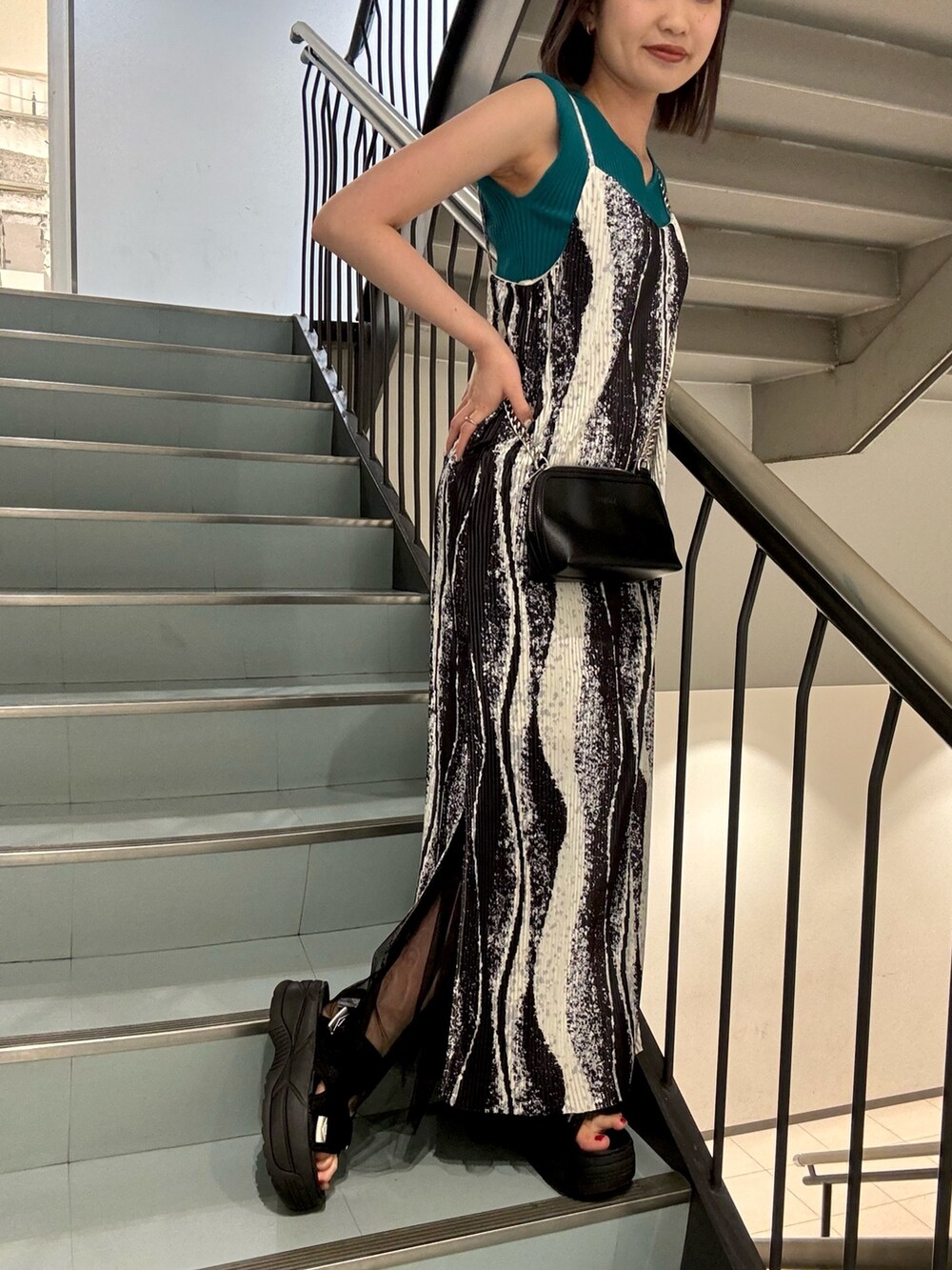 ブラック系のワンピース、ブラック系のハンドバッグ、グリーン系のニット/セーターを着用したレディースの春コーディネートの4枚目の写真