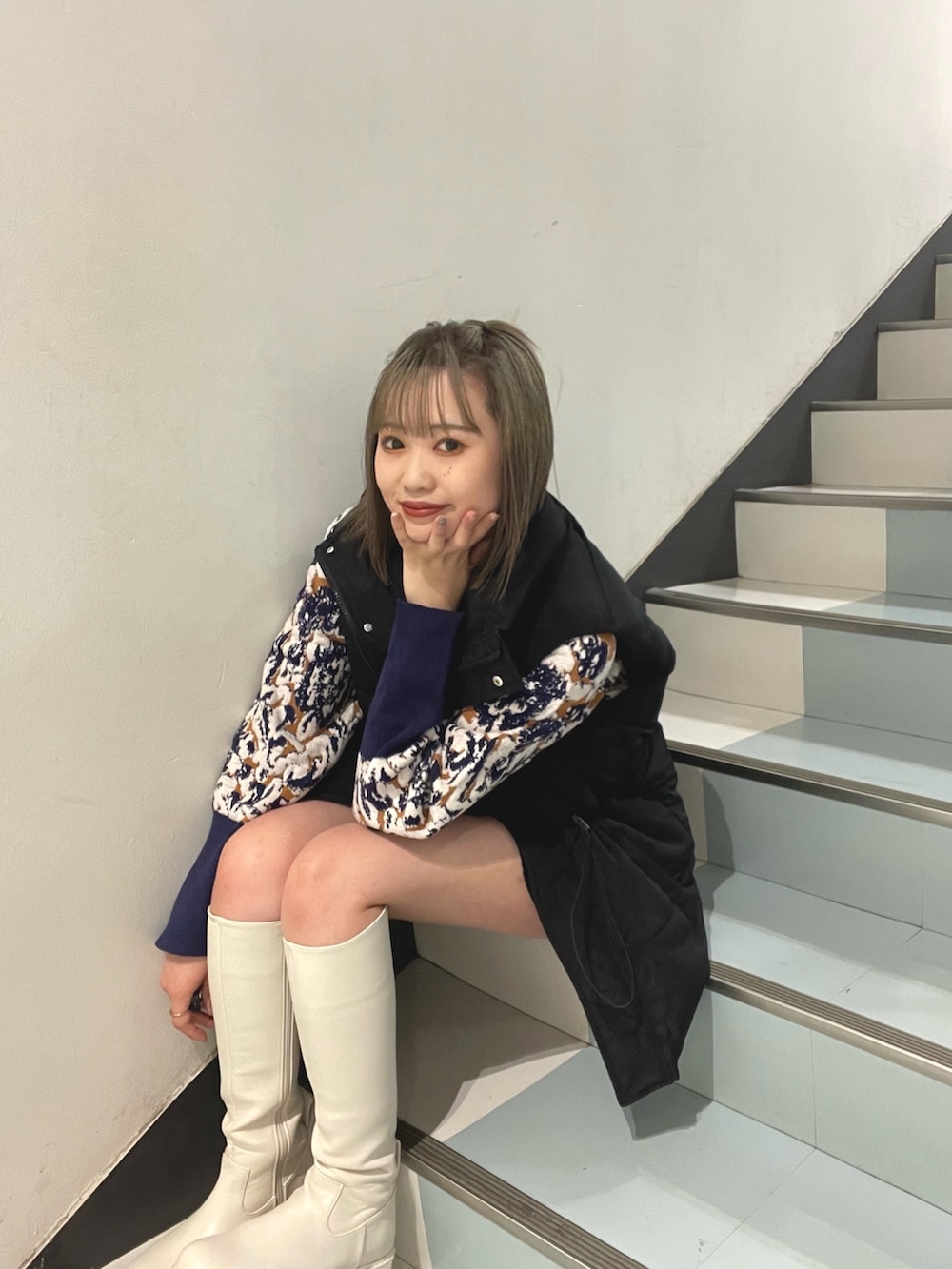 グリーン系のハンドバッグ、ブラック系のダウンベスト、ホワイト系のブーツを着用したレディースの秋コーディネートの3枚目の写真