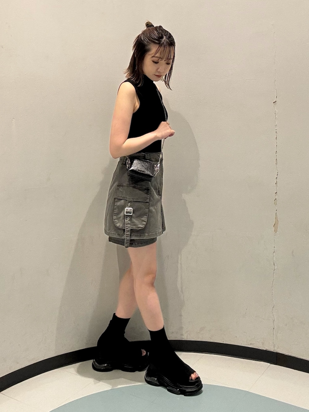 ブラック系のニット/セーター、ブラック系のサンダル、グレー系のスカートを着用したレディースの夏コーディネートの2枚目の写真