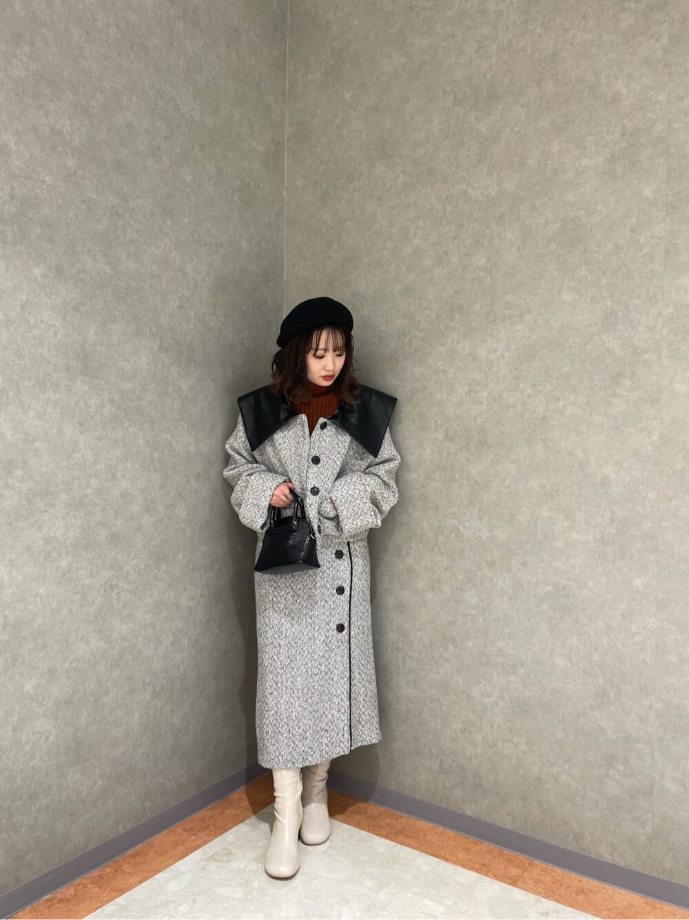 ホワイト系のブーツ、ブラック系のハンドバッグ、ホワイト系のスカートを着用したレディースの秋コーディネートの5枚目の写真