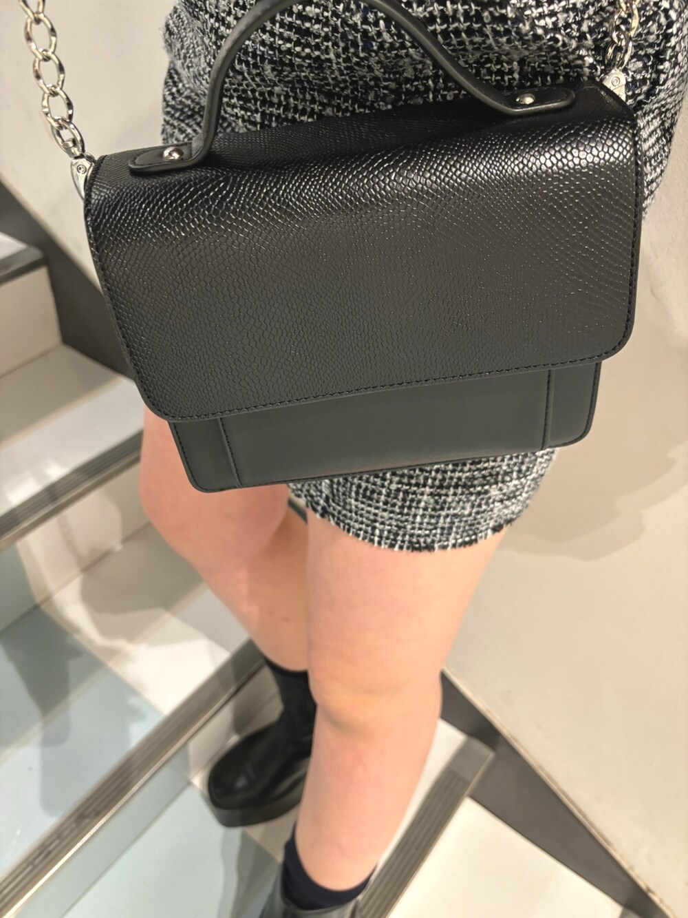 ブラック系のハンドバッグ、ブラック系のニット/セーター、ブラック系のワンピースを着用したレディースの冬コーディネートの6枚目の写真