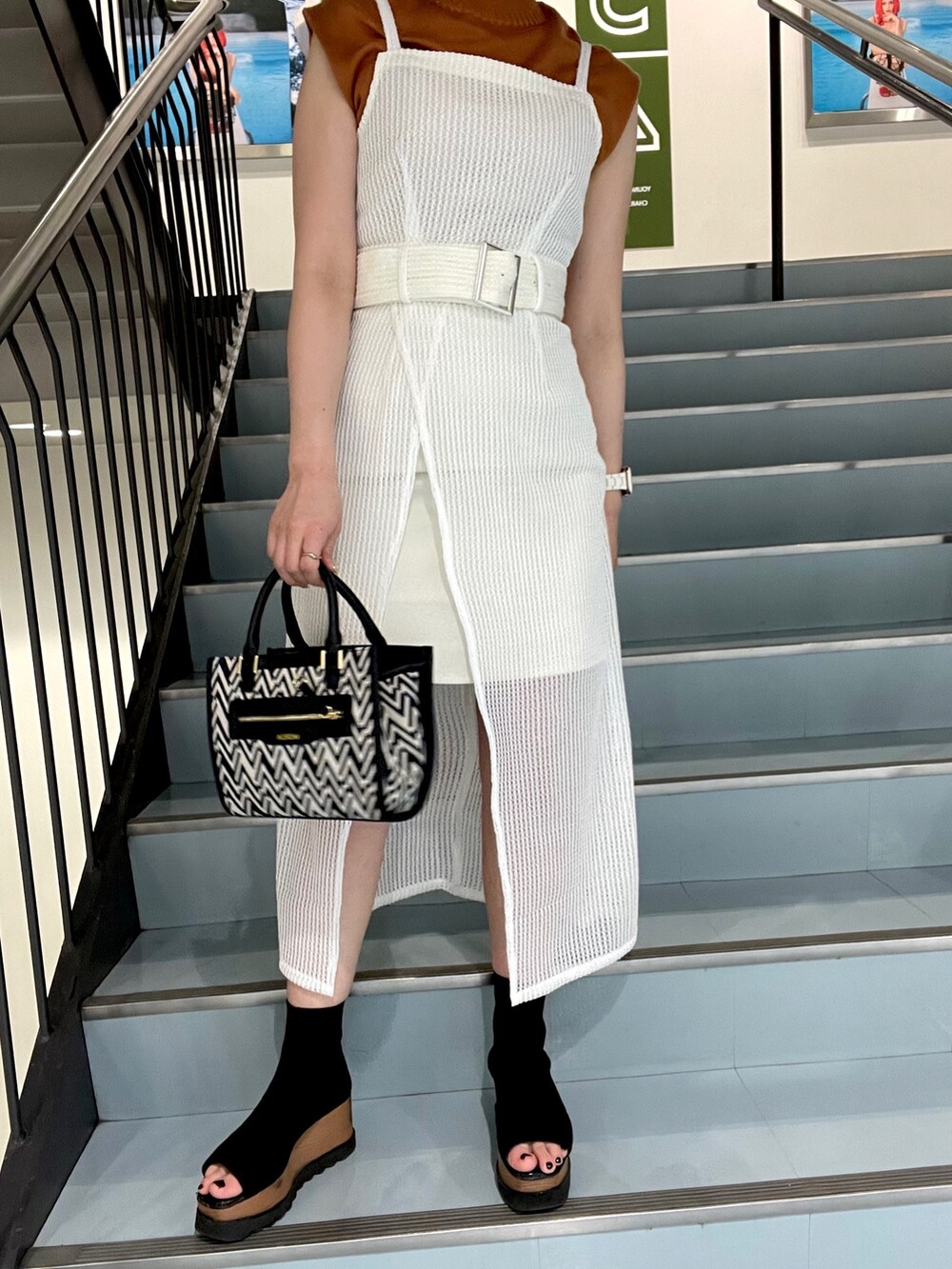 オレンジ系のニット/セーター、その他のショルダーバッグ、ホワイト系のワンピースを着用したレディースの春コーディネートの5枚目の写真