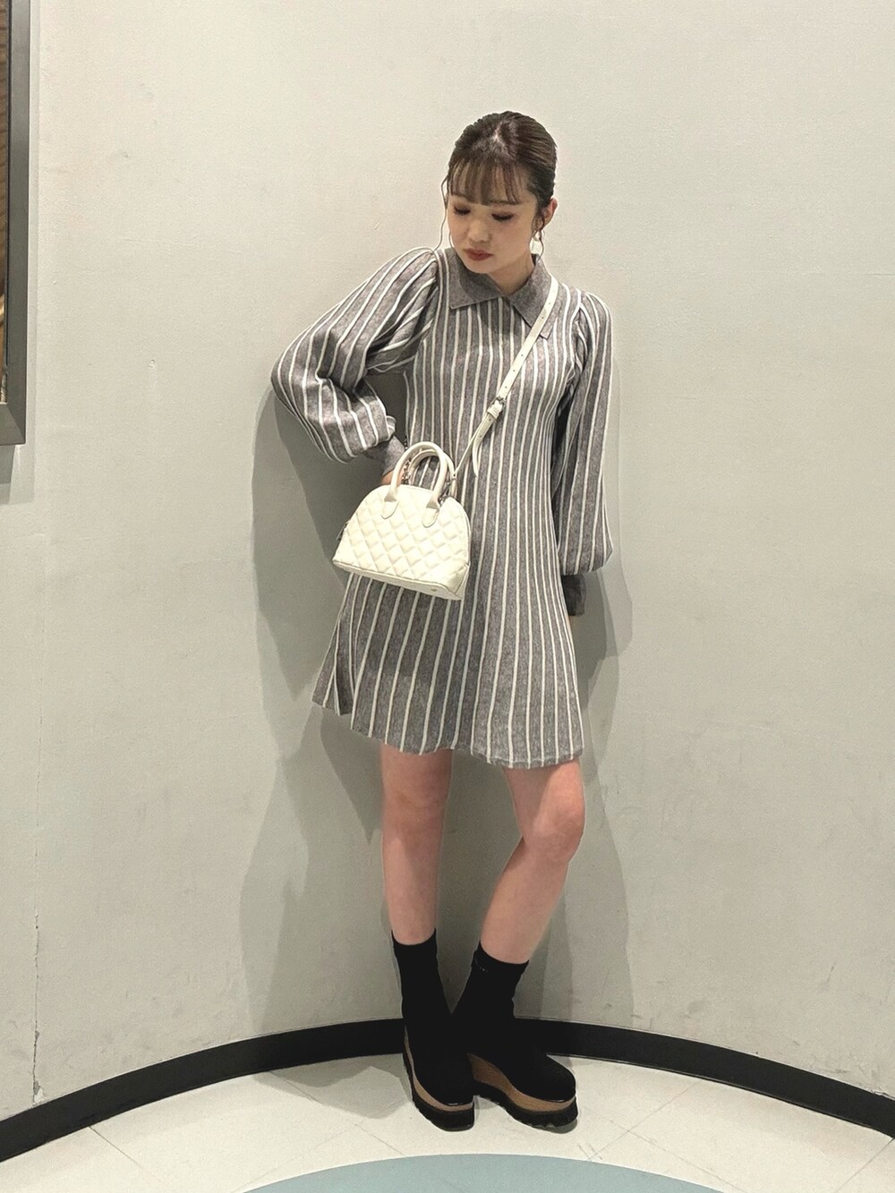 ホワイト系のブルゾン、ホワイト系のハンドバッグ、ブラック系のブーツを着用したレディースの冬コーディネートの4枚目の写真