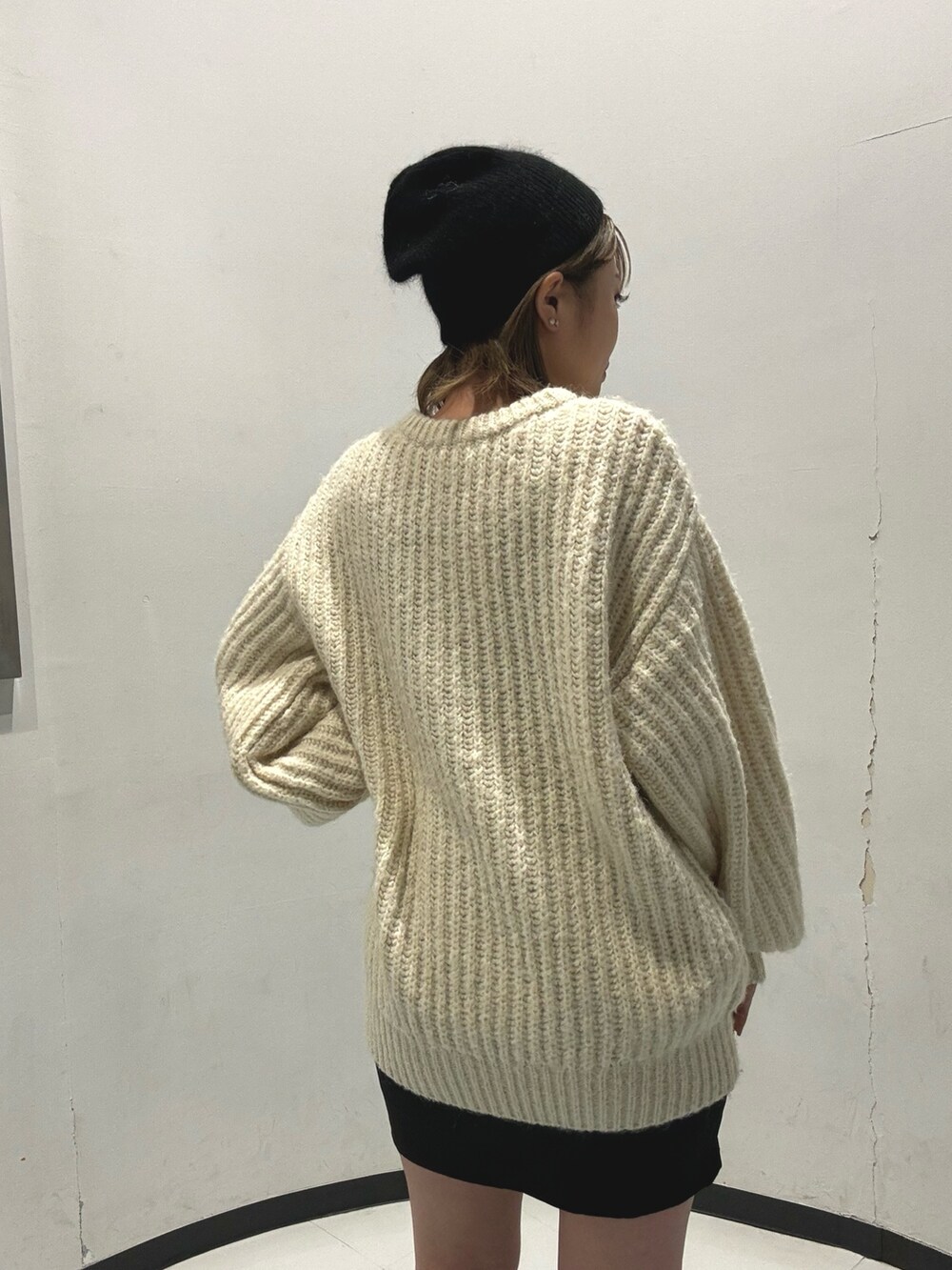 ブラック系のスカート、ホワイト系のニット/セーター、グリーン系のブーツを着用したレディースの秋コーディネートの5枚目の写真