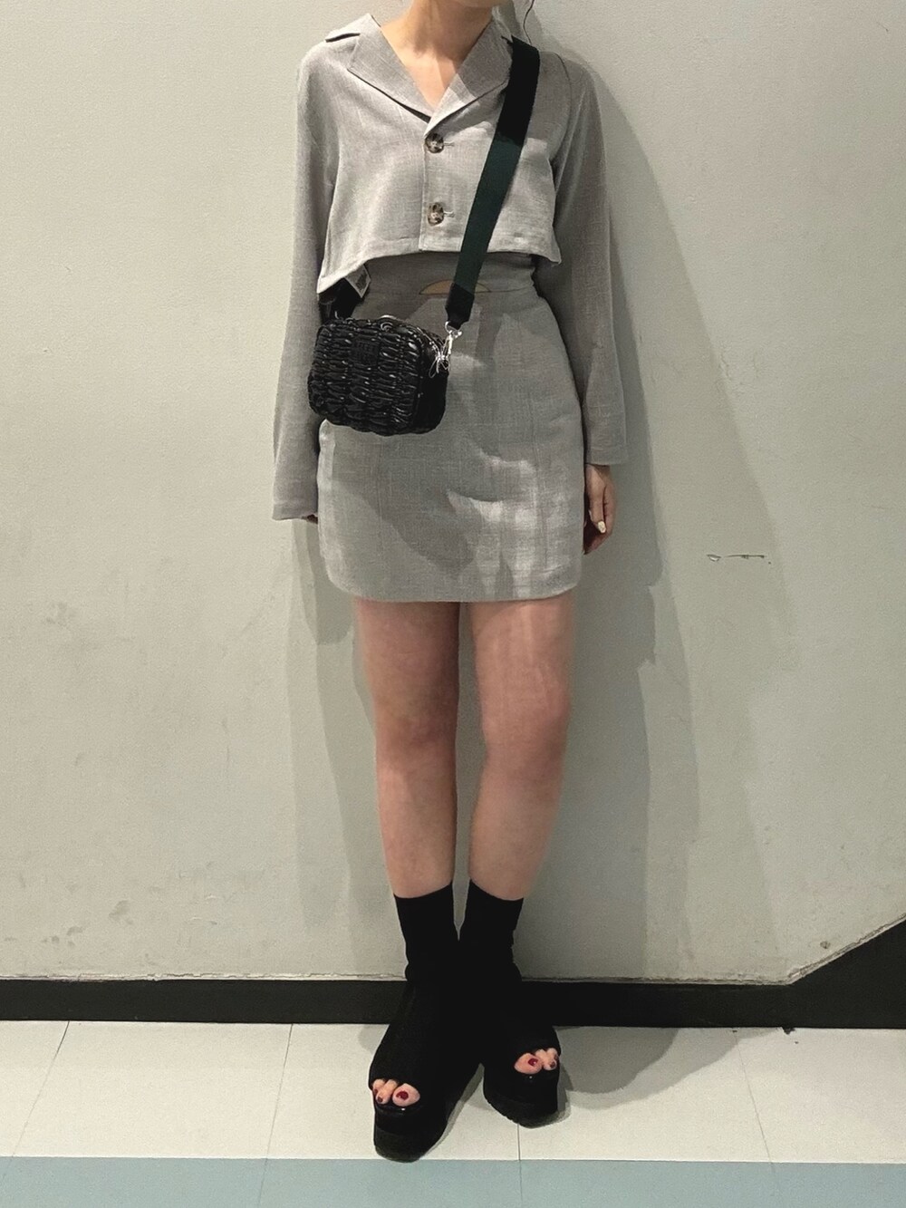 ブラック系のショルダーバッグ、グレー系のワンピース、ブラック系のブーツを着用したレディースの春コーディネートの5枚目の写真