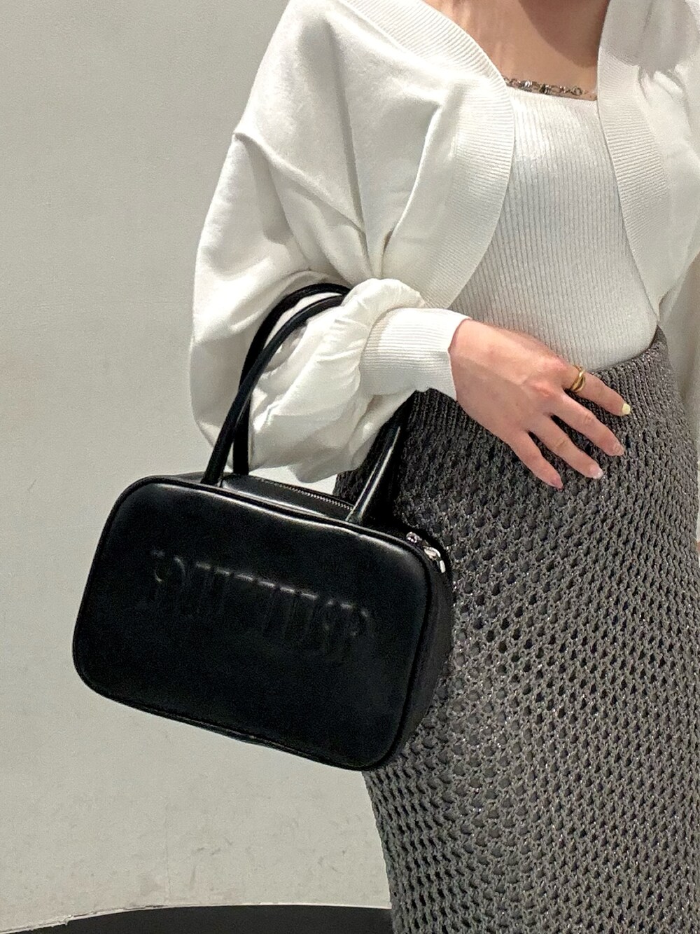 ホワイト系のカーディガン/ボレロ、グレー系のスカート、ブラウン系のブーツを着用したレディースの秋コーディネートの6枚目の写真